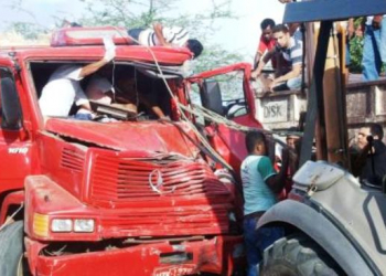 Caminhoneiro fica preso nas ferragens ao colidir com  caçamba