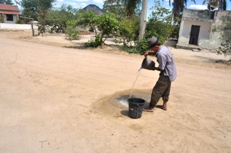 Agricultor abastece recipiente para saciar sede de pássaros