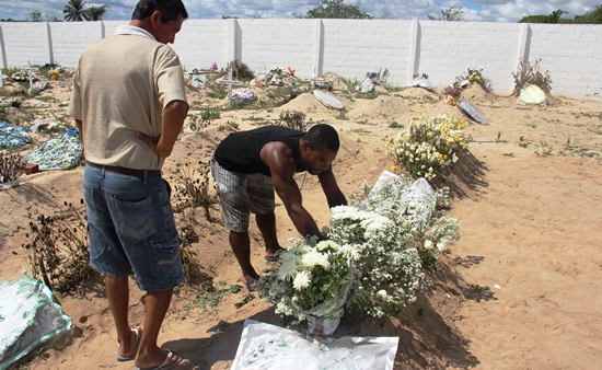 Coveiro arruma a sepultura de Janiele com as flores depositas pelos familiares e amigos.