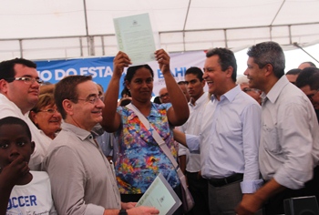 Titulo de terra erguido como troféu pela agricultora.