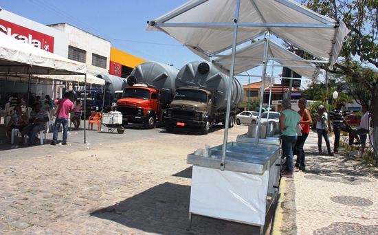 Modelo das barracas entregues e ao fundo as cisternas nos caminhões.