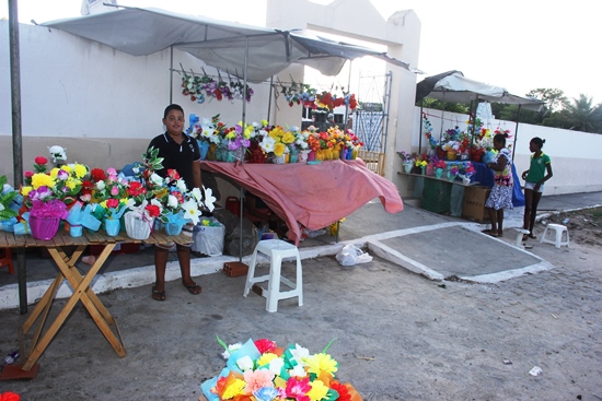 Em frente ao cemitério velho ramalhetes de flores artificias sendo vendido pelo valor de R$ 2 a R$ 20.