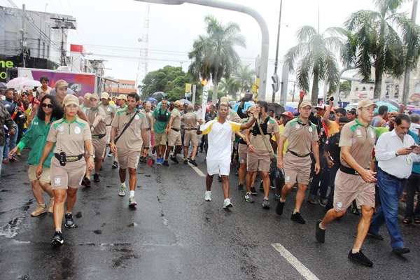 Debaixo de chuva Tocha Olímpica percorre avenidas de Feira de Santana
