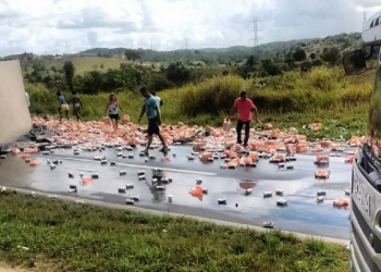 Carreta carregada de cerveja em lata tomba na BR 324 e populares ‘fazem a festa’