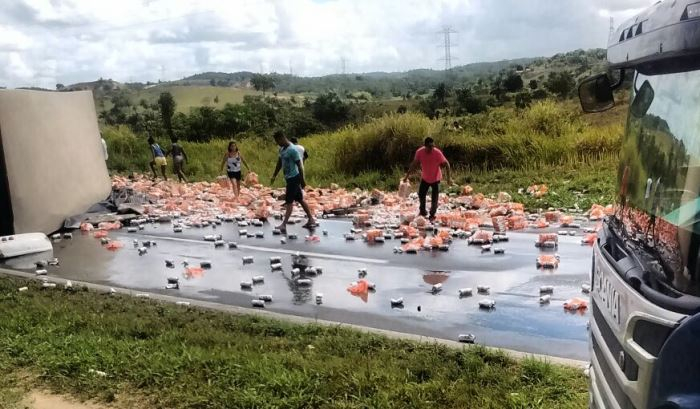 Carreta carregada de cerveja em lata tomba na BR 324 e populares ‘fazem a festa’