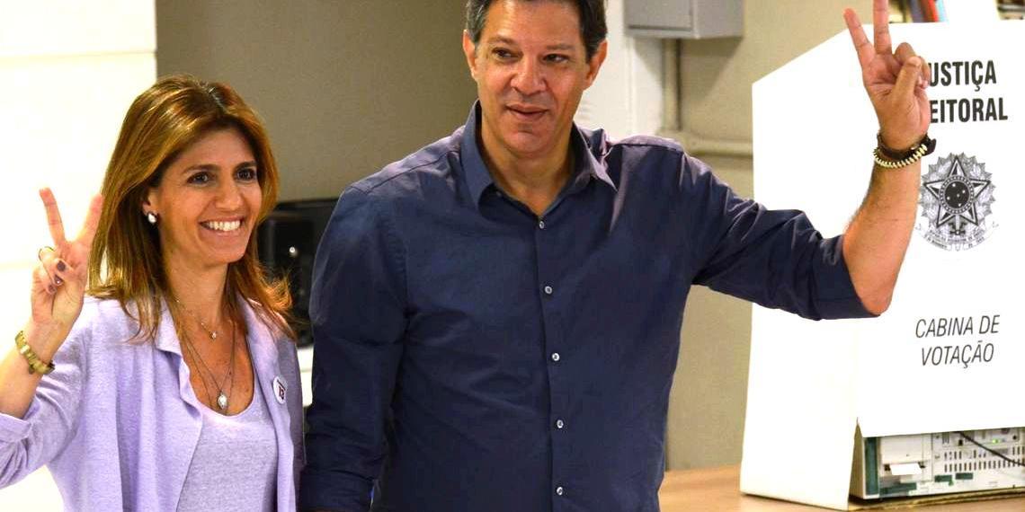Com camisa azul, Haddad vota e faz sinal de vitória