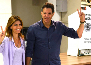 Com camisa azul, Haddad vota e faz sinal de vitória
