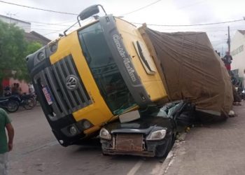 Caminhão carregado de maracujá tomba sobre carro de passeio estacionado
